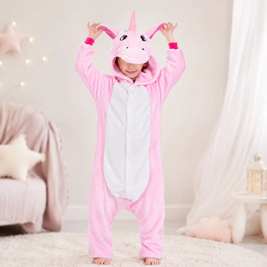 petite fille qui se tient debout qui lève les oreilles de son kigurumi licorne pour enfant rose avec ses mains